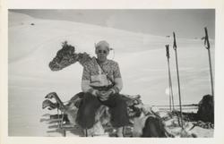 Olav O. Vågen med lusekofte og solbriller sitter på et felt 