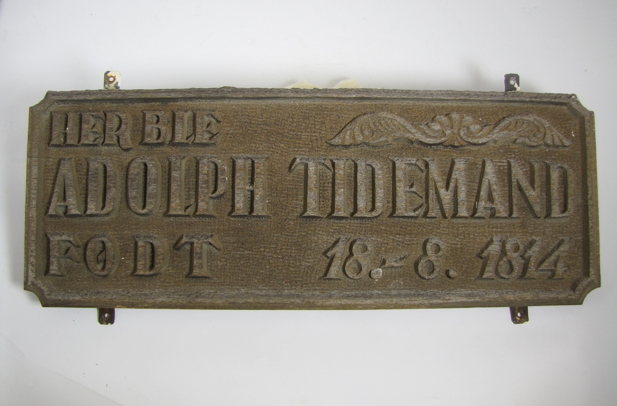 Plakett med teksten: "Her ble Adolph Tidemand født 16-.8. 1814"