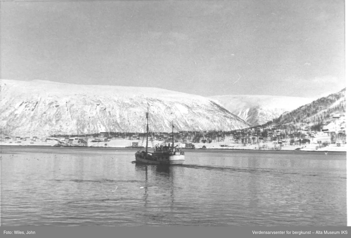 Ishavsskute i Tromsø, fjell og bebyggelse i bakgrunn.
