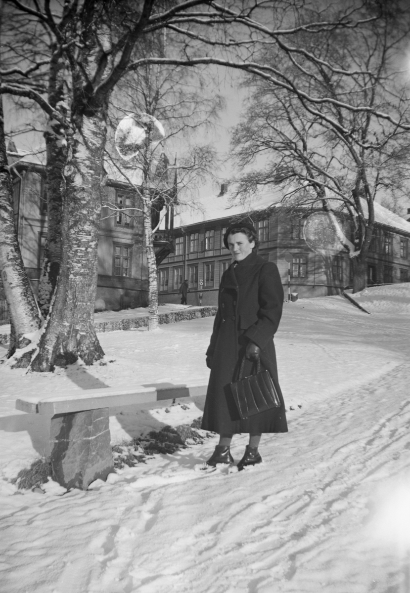 Kvinne står i Søndre Park, Lillehammer. Astrupgården til venstre og Wiesegården til høyre
