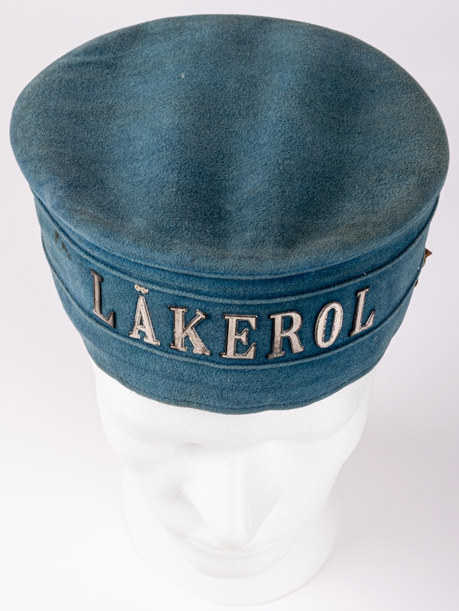 Hatt i blå sammet med text i metall: "LÄKEROL".