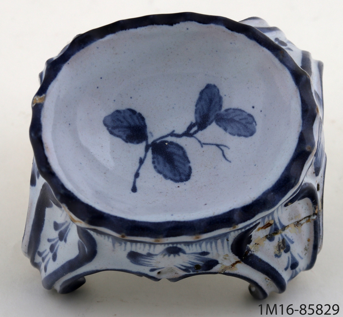 Saltkar, av vitt porslin med målad dekor i blått. Möjligen kinesiskt. Oval skålform med fyra svängda ben.