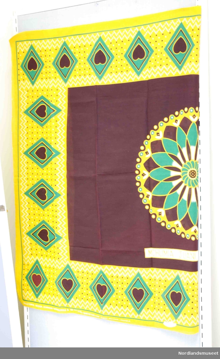 2 stykker skjal/sarong/kjole i bommullstoff påtrykt mønster i brunt, gult og grønt.
Det ene noe falmet på en del av stoffet.