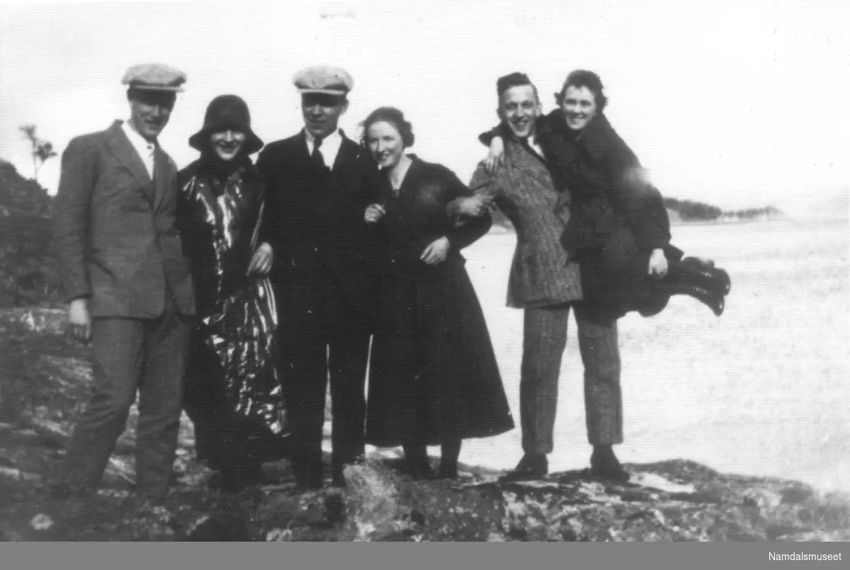 En munter ungdomsgjeng samlet ved sjøen. Tre kvinner og tre menn. Hans, Hjørdis, Karlgård, Eli, Thorvald, Dagma D.