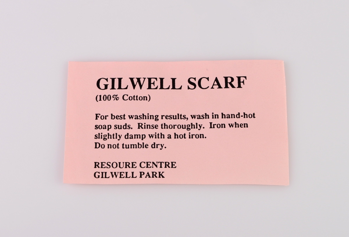 Vaskeanvisning for Gilwell-skjerfet (skjerf man mottar når man har gjennomført Gilwell-treningen som er den høyeste internasjonale lederutdanningen innen  speiderorganisasjonen). Den er laget av rosa papir med svart tekst. For tekst se "Påført tekst/merker".