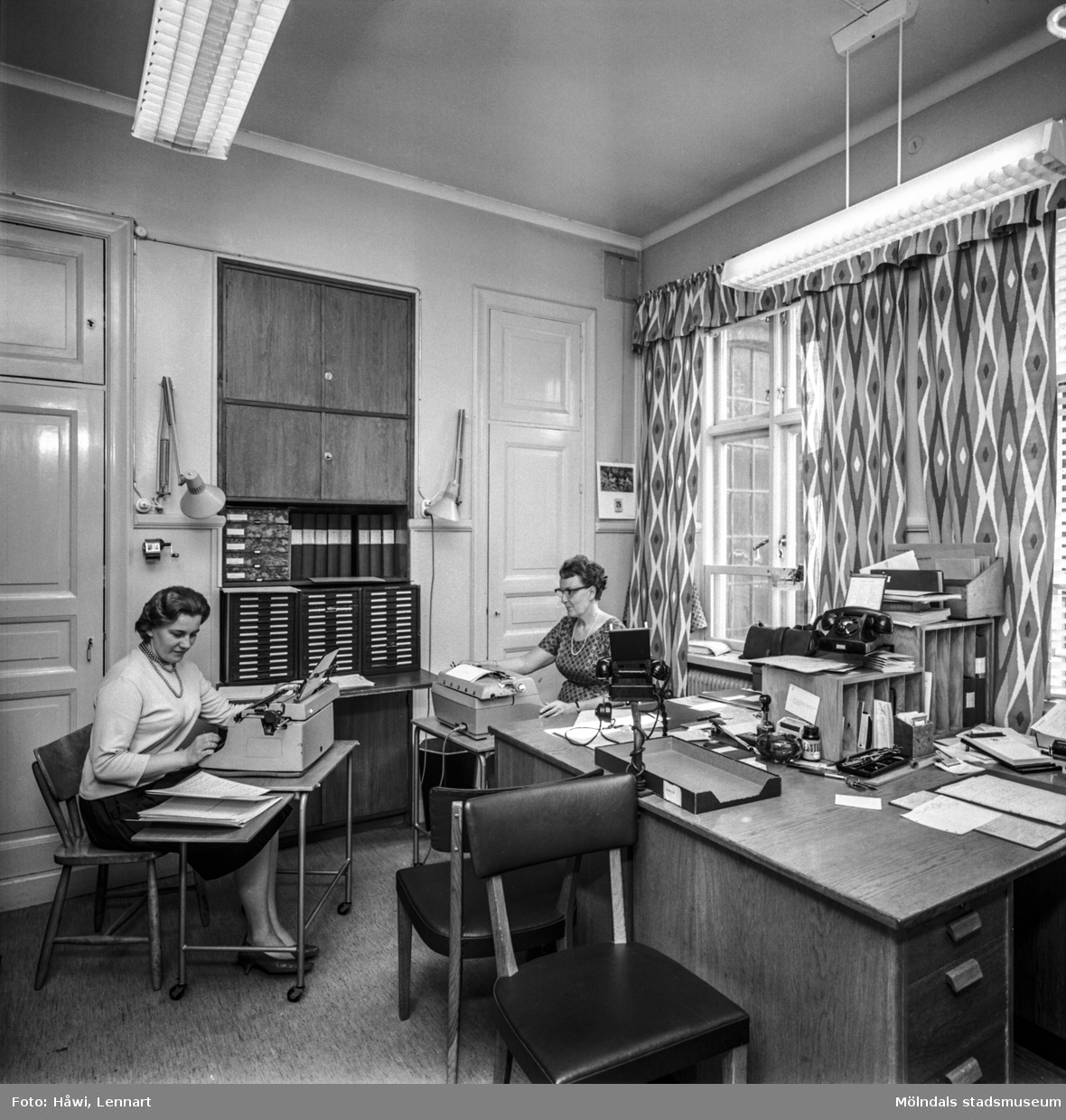 Interiörbild från pappersbruket Papyrus i Mölndal, 25/5 1964. Två kvinnor arbetar i ett kontor.