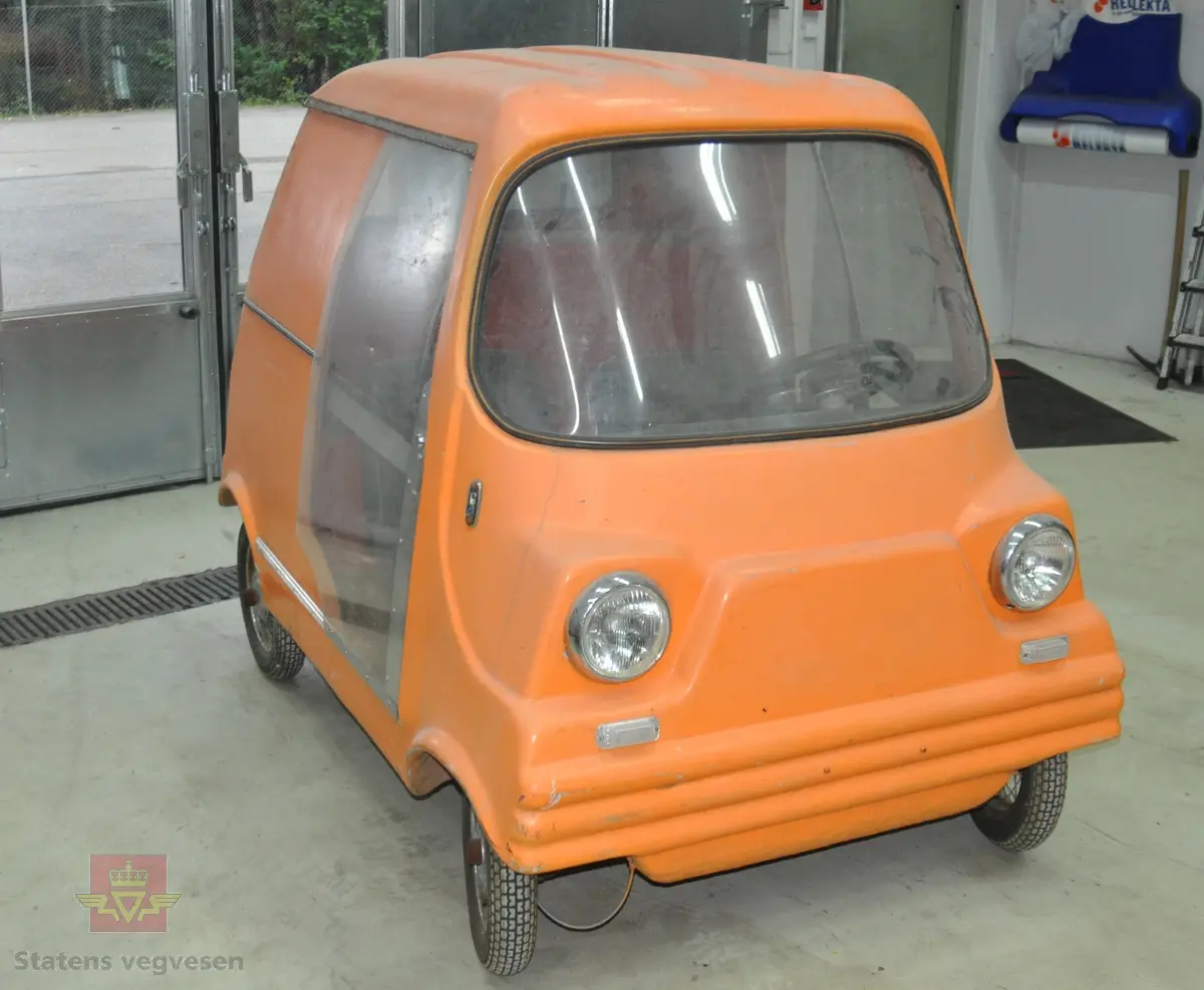 Oransje elektrisk kjøretøy laget i glassfiber. Denne prototypen har bare plass til fører. Rammen er en enkelt ståkonstruksjon og hjulene er av tralletypen. Den hadde konvensjonelt blybatteri og elmotor fra en vaskemaskin.