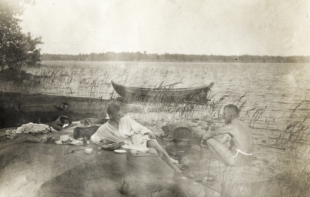 Två män i badkläder på en bergshäll. I bakgrunden syns en roddbåt.
Text under fotot: " - Vi höllo gärna - till på Hästskoö - där vi oftast övernattade - ".