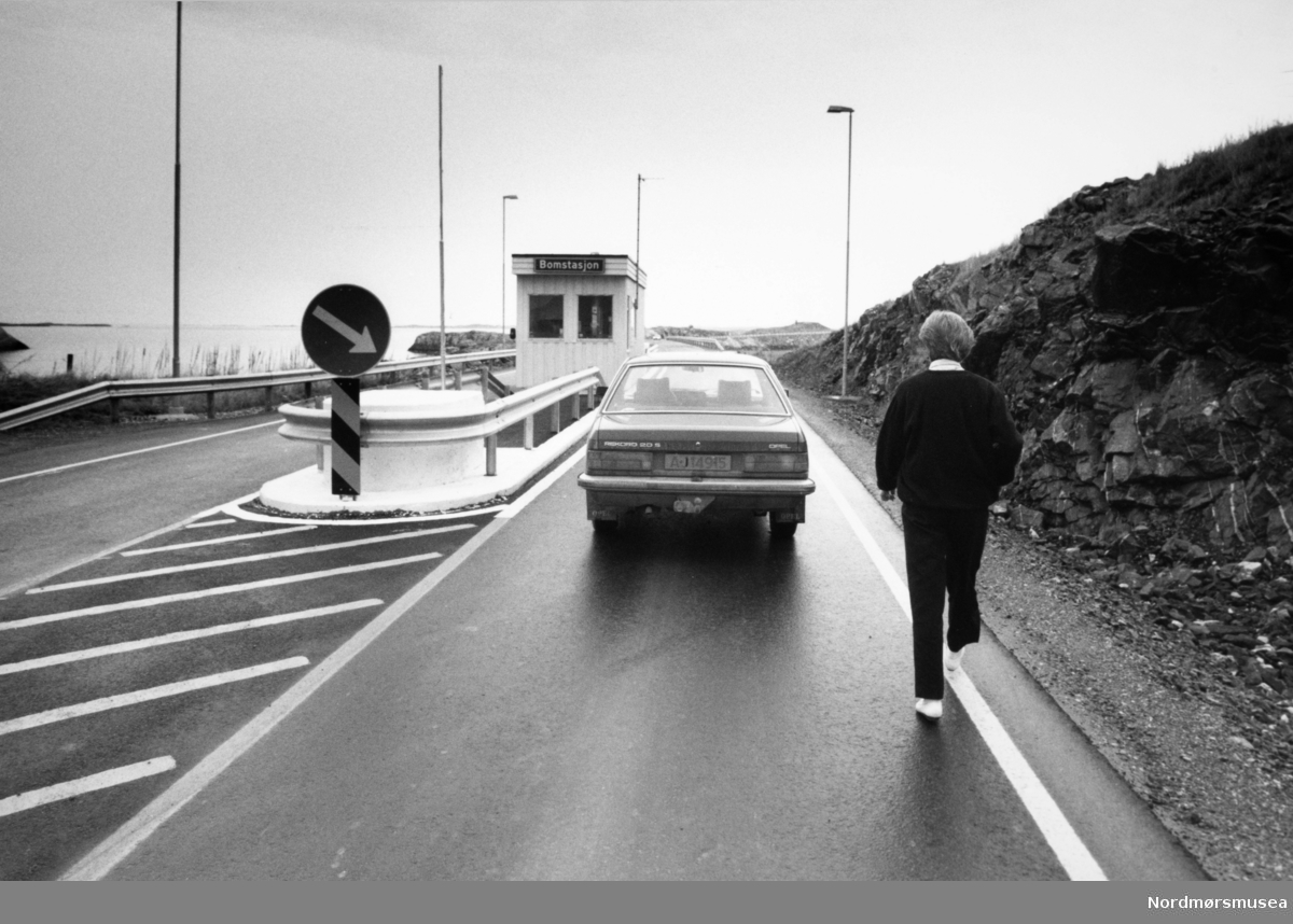 Fra bomstasjonen ved Atlanterhavsveien mellom Averøy og Eide i Møre og Romsdal, 7. juli 1989. Atlanterhavsveien er en veistrekning på 8.274 meter. Anlegget består av åtte broer på til sammen 891 meter og går over holmer og skjær. Veien kostet 122 millioner i 1989 og var delvis bompengefinansiert. Anlegget ble åpnet 7. juli 1989 og bommen ble fjernet i juni 1999. Atlanterhavsveien er landets åttende best besøkte naturbaserte turistattraksjon (2004) med 283.500 besøkende. Veistrekningen er foreslått vernet i "Nasjonal verneplan for veger, bruer og vegrelaterte kulturminner." (Kilde: Wikipedia Norge).
