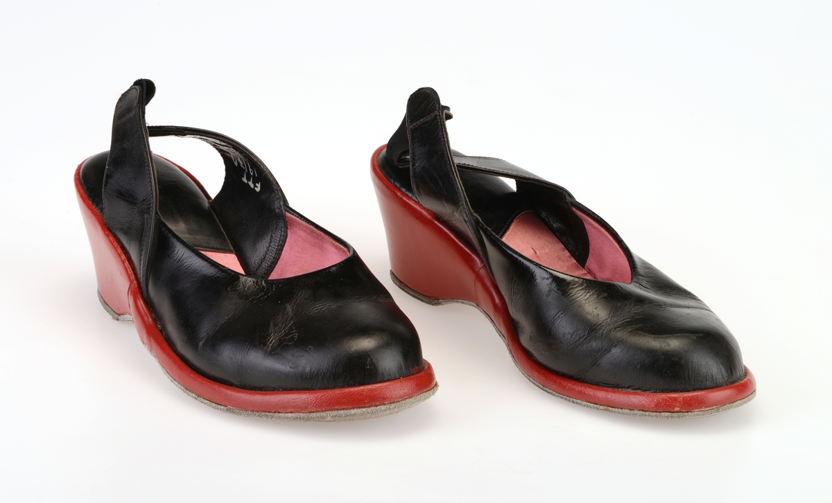 Et par dametøfler av skinn/lær med kilehæl. Overdelen av skoen er av svart lær, mens kilehælen og den nedre delen av skoen er av rødt lær. De er foret med rosa silkefor. På hælen er det svart skinn. Skoene har hælstropper av svart fløyel. Stroppene er elastiske. Yttersålen er av grå semsket lær.
