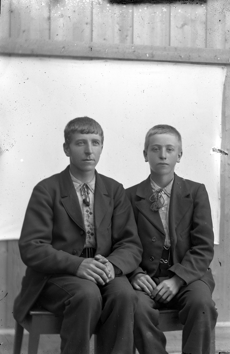 To unge menn i dress, sitter.