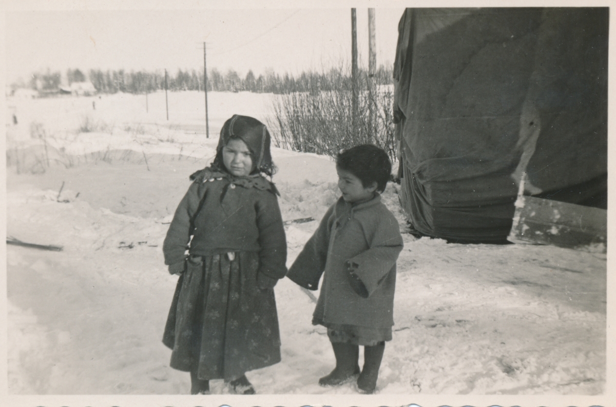 Två små barn i ett snövitt landskap.