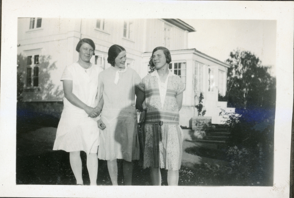 Elever fra husmorskolen på Skansgården, Kongsvinger, 1928. Tre unge kvinner i hagen utenfor huset.
