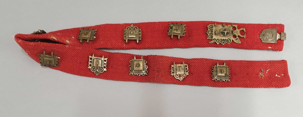 Rødt belte av ull, med 9 messingstøler og to beltespenner i den ene enden.