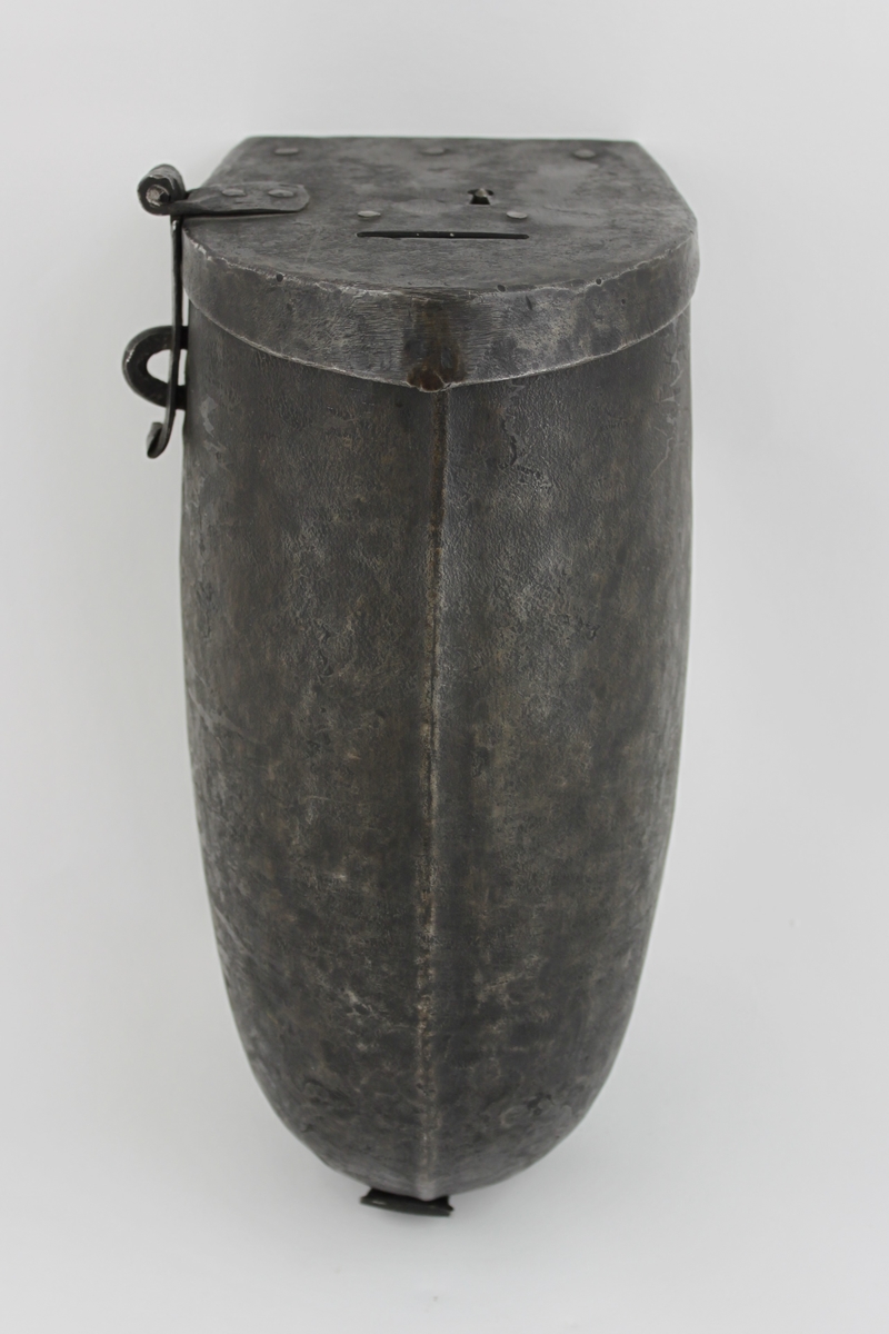 Brevbehållare eller kassaskrin av järnplåt med formen av en halvcylinder.
Lås i lock på gångjärn på ovansidan.