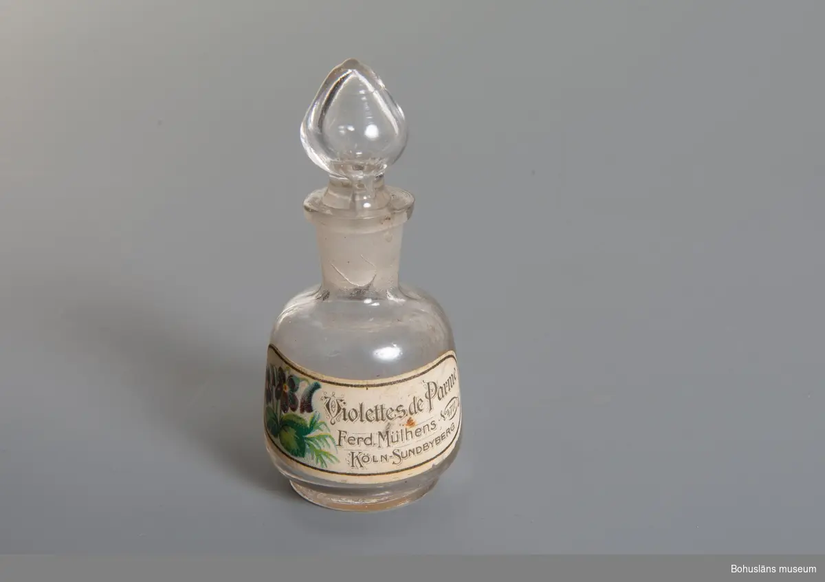 Parfymflaskan har form av en karaff med glaspropp. Med etikettskrift: "Violettes de Parme" "Fred Mülhens No 4711 Köln-Sundbyberg", och bild på en violplanta.