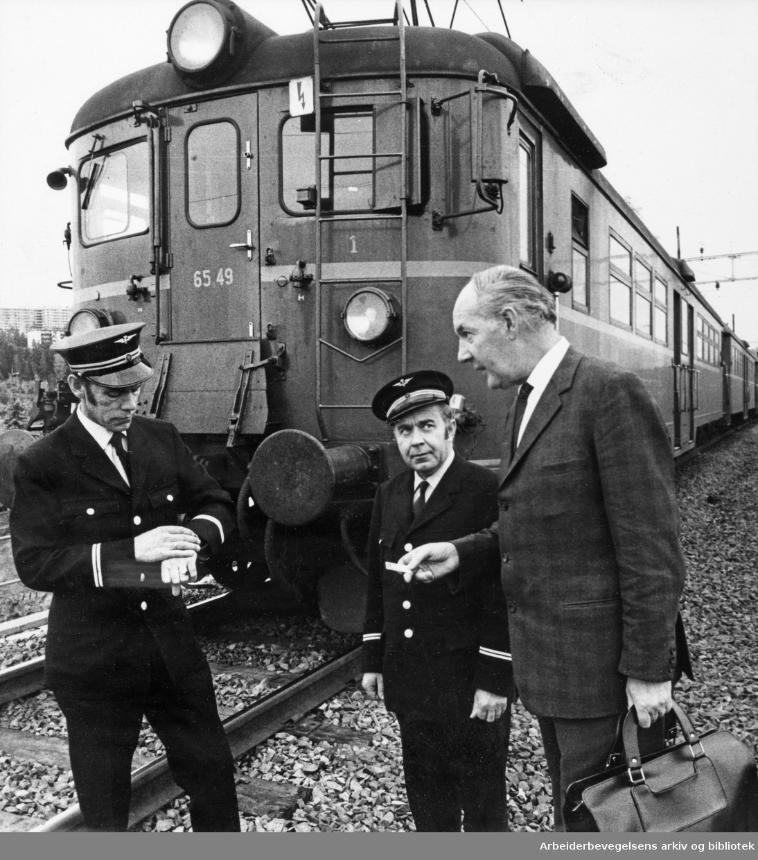 Landsomfattende LO-streik i 15 minutter mot Borten-regjeringens budsjett 7. Oktober 1970. Lokfører Arne Skogly og konduktør Arne Nilsen. Til høyre, passasjer Teddy Kloster. Bildet er tatt like ved Alnabru stasjon.
