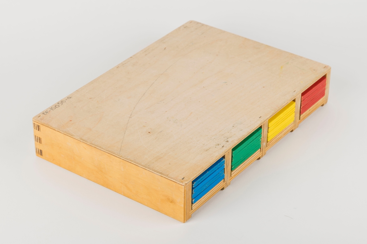 Spillboks med 12 figurbrikker og 20 flate, rektangulære brikker. Figurbrikkene stikkes i hull i spillboksen og går gjennom hull i de flate brikkene. Hullene har en diameter på 2,7 cm.

3 røde, 3 blå, 3 gule og 3 grønne figurbrikker. Brikkene måler 11 x 2,5 cm. 

4 røde, 4 blå, 4 gule, 4 grønne og 4 trefargede flate brikker. Brikkene måler 19,5 x 5,6 cm og er 0,6 cm tykke.