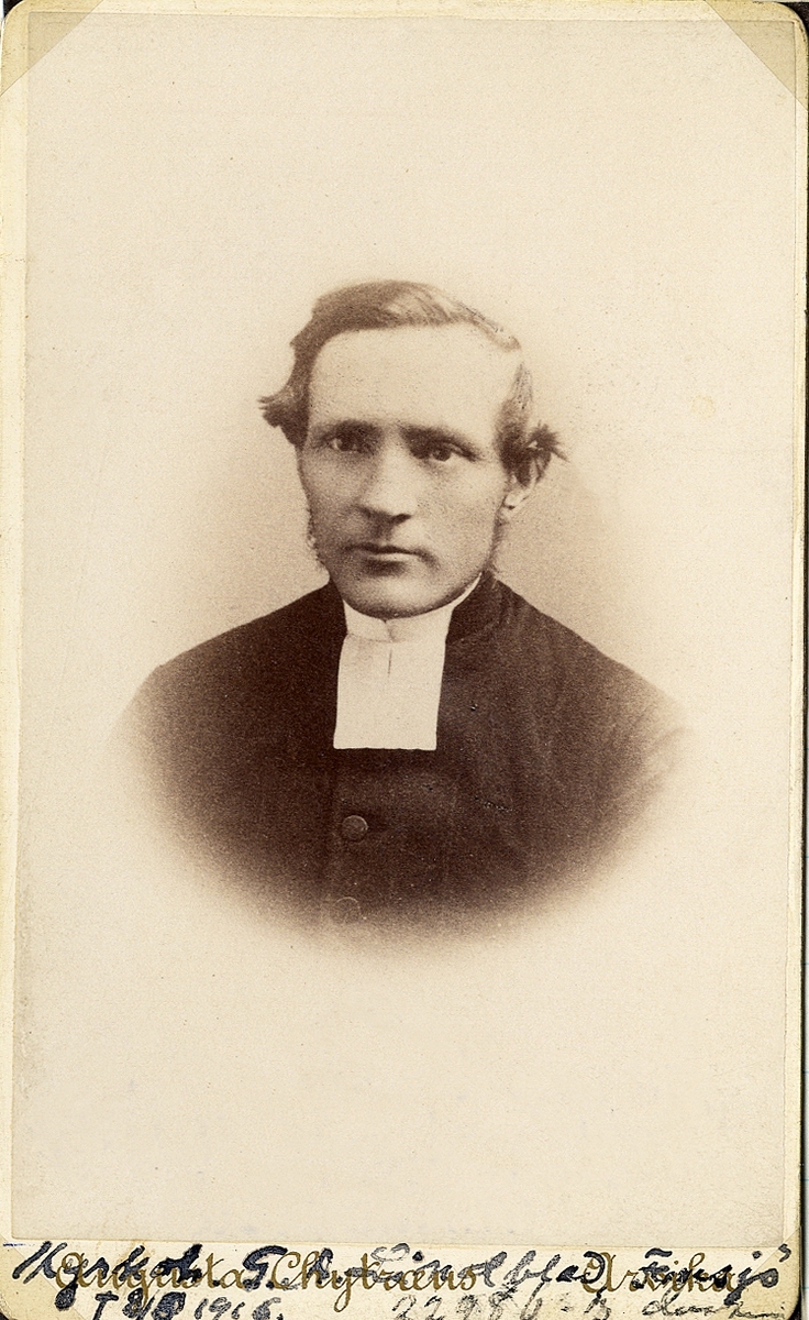 Porträttfoto av en man i prästrock och prästkrage. 
Bröstbild, halvprofil. Ateljéfoto.