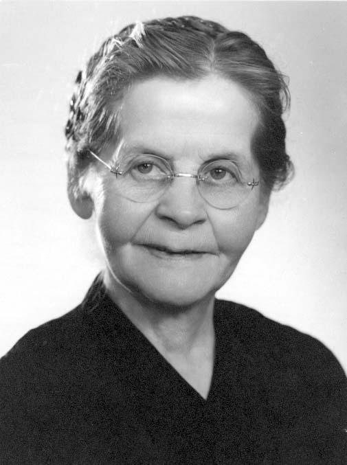 Porträtt av en äldre kvinna med runda glasögon.
