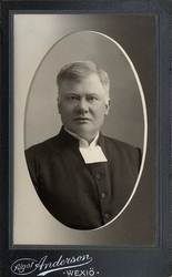 Foto av en man i prästrock och prästkrage. 
Bröstbild, halvp