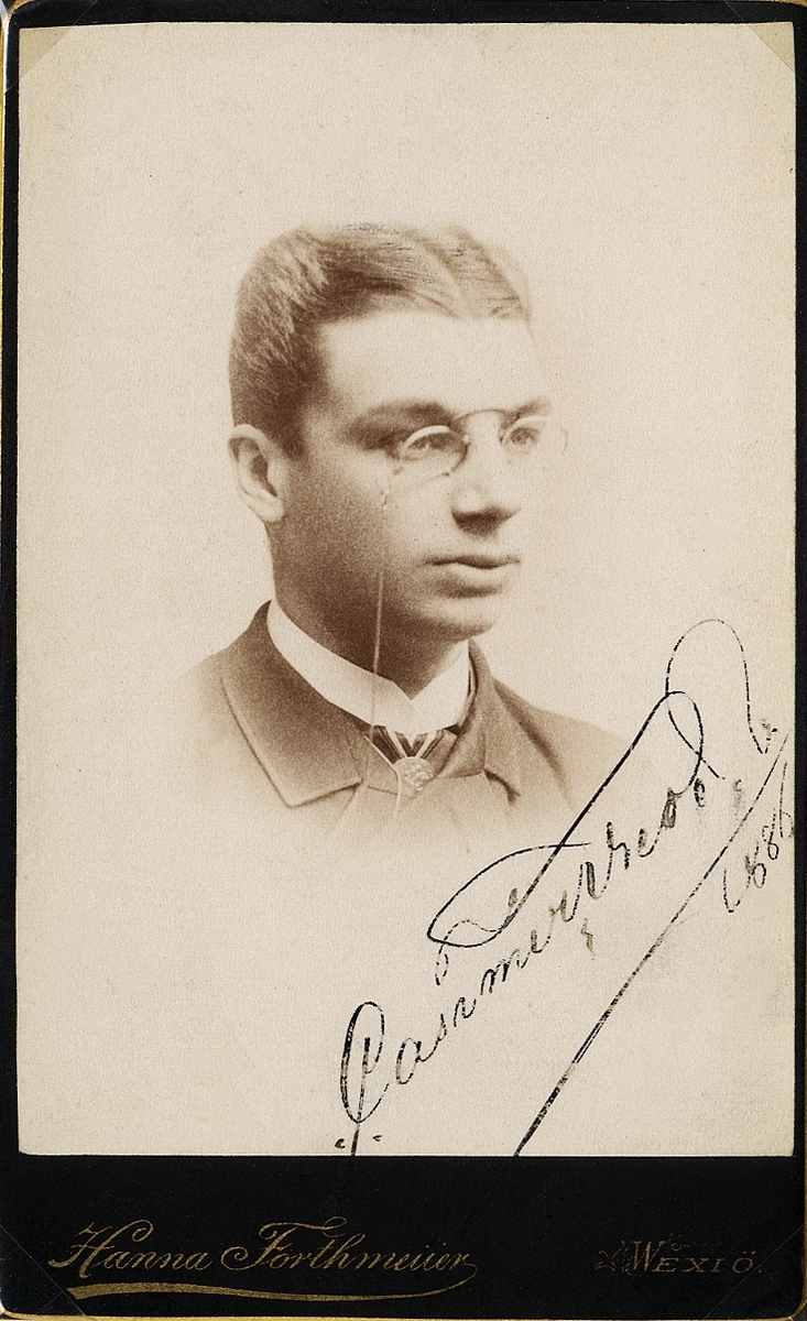 Foto av en ung man med pincené, klädd  i kavajkostym med stärkkrage och slips. 
I nedre högra hörnet syns autograf: "Casimir Wrede, 1886".
Bröstbild, halvprofil. Ateljéfoto.