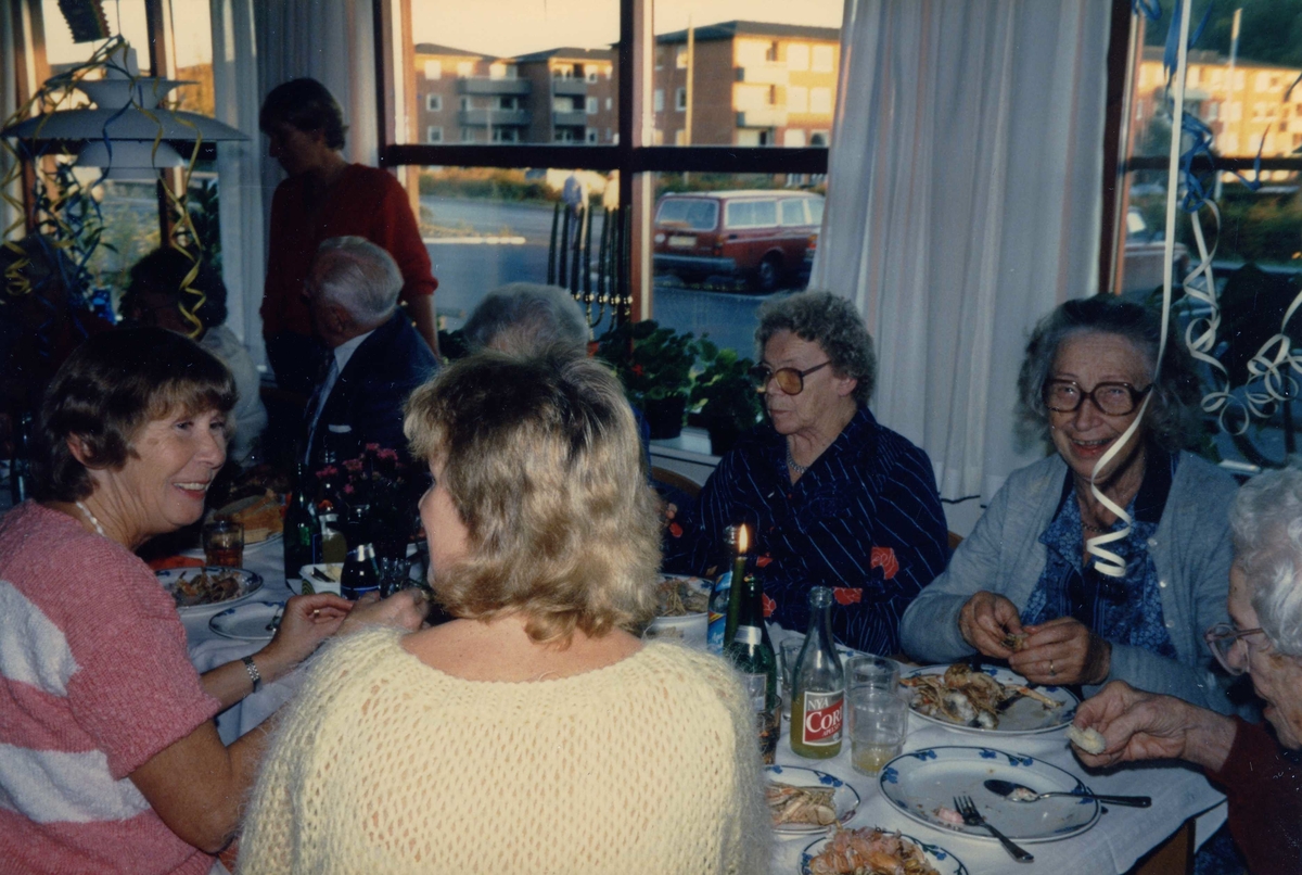 Kräftskiva på Brattåsgården (Streteredsvägen 5), troligtvis år 1989. Från vänster ses vårdbiträde 1. Greta Nilsson (rosa tröja), 2. Henrik Lundell (bortvänd), 3. Elvira Jägnert (mörk klänning) och 4. Marianne Skarin (med glasögon, skrattar).