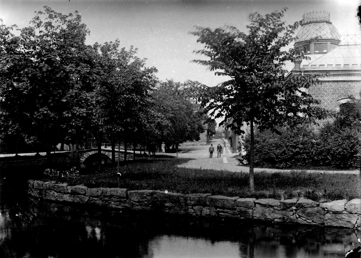 Människor promenerar längst Lillån vid Varmbadhuset med Färgeri- eller Fattighusbron till vänster.