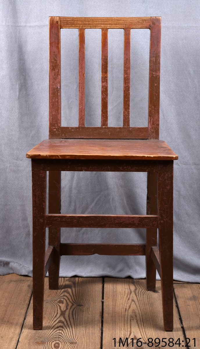 Enkla stolar med raka ben, 3 vertikala spjälor i rygg, tvärslåar. Brunmålade.