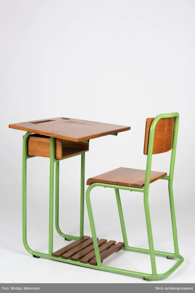 En sammenhengende stol-bord til en person. Stol- og bordbein av metallrør, sete, ryggstø og bordplate av finer.