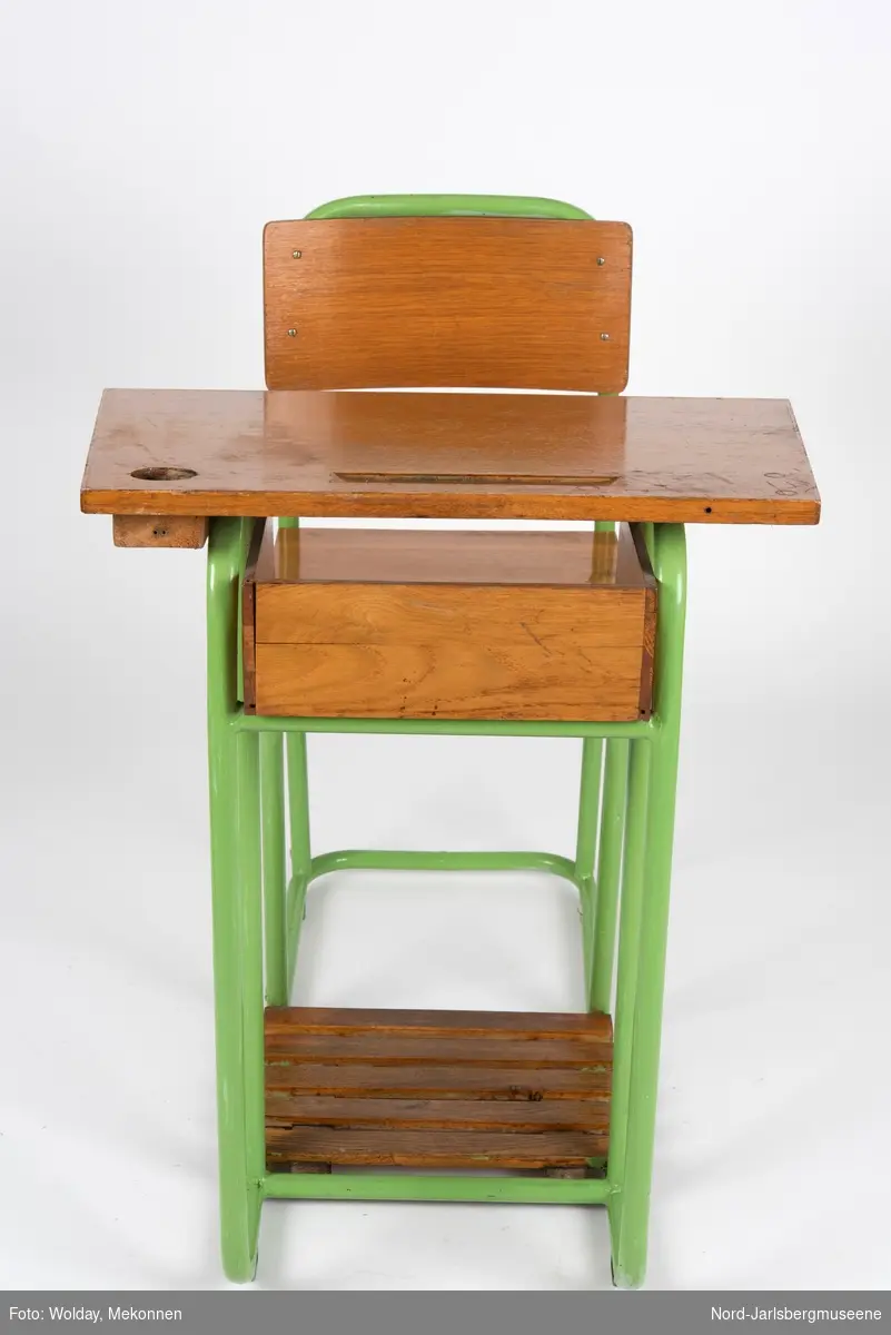 En sammenhengende stol-bord til en person. Stol- og bordbein av metallrør, sete, ryggstø og bordplate av finer.
