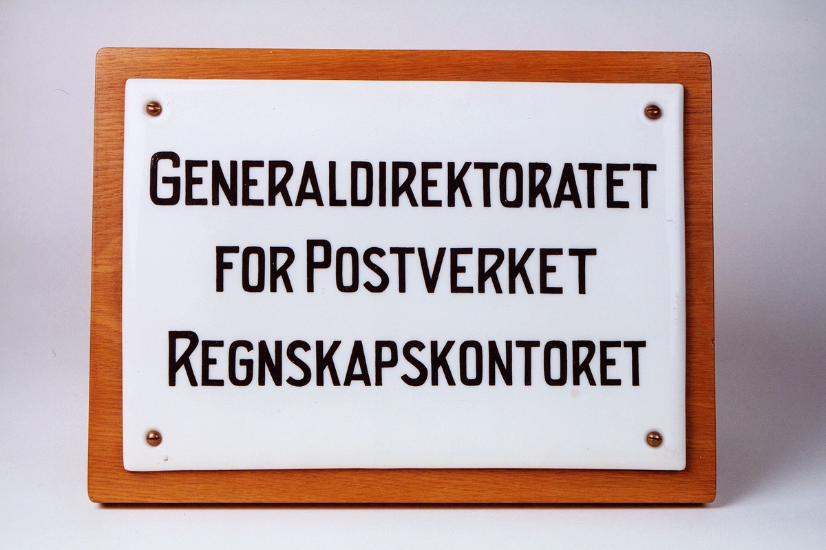 Skiltet er påsatt treplate. Skiltet har sort skrift. Det er brukt i Poststyret. Generaldirektoratet for postverket, regnskapskontoret.
