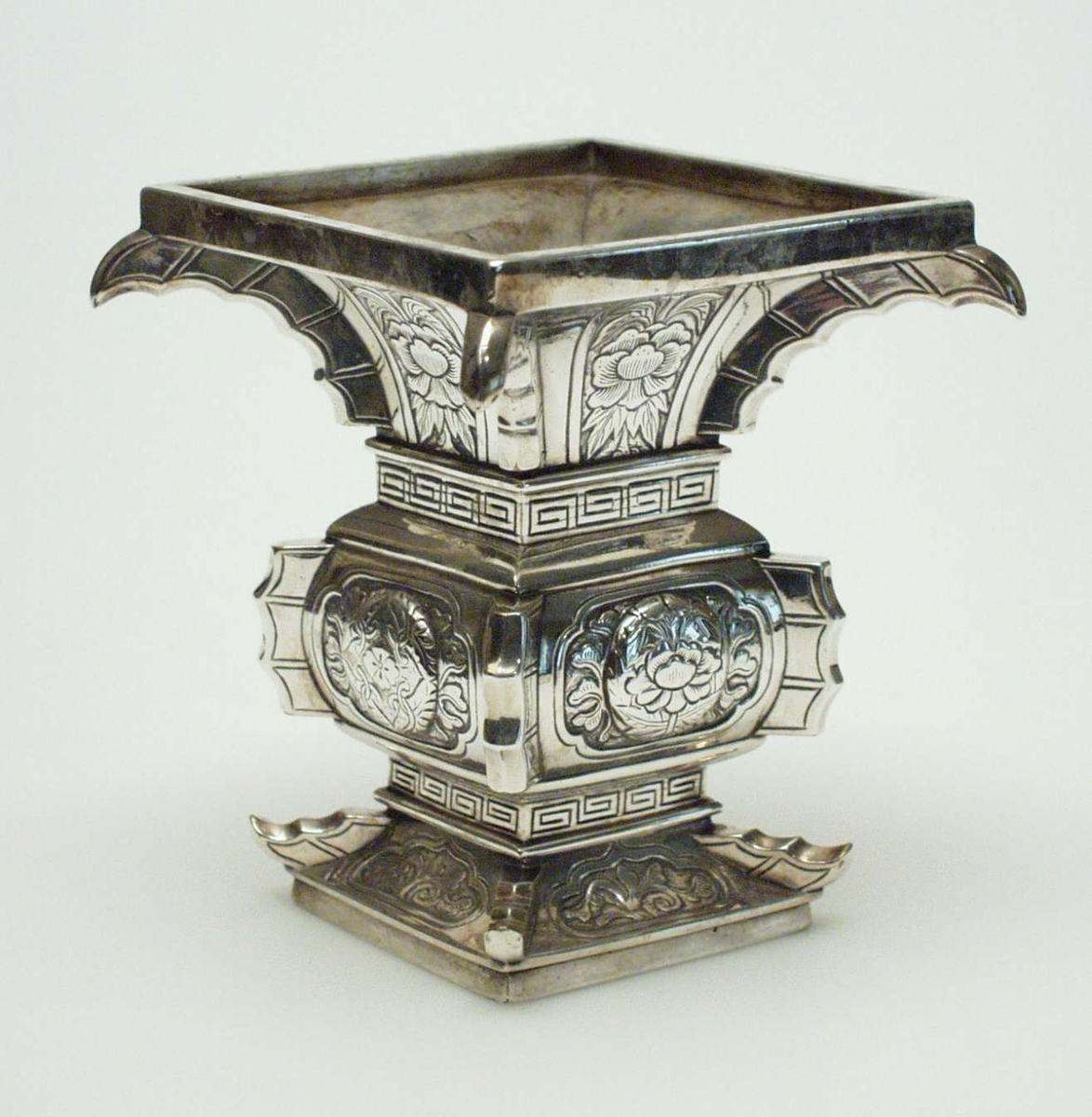 Firkantet vase i sølv dekorert med forsiringer og meanderborder (a ´la´greque). Utsvungen hals.