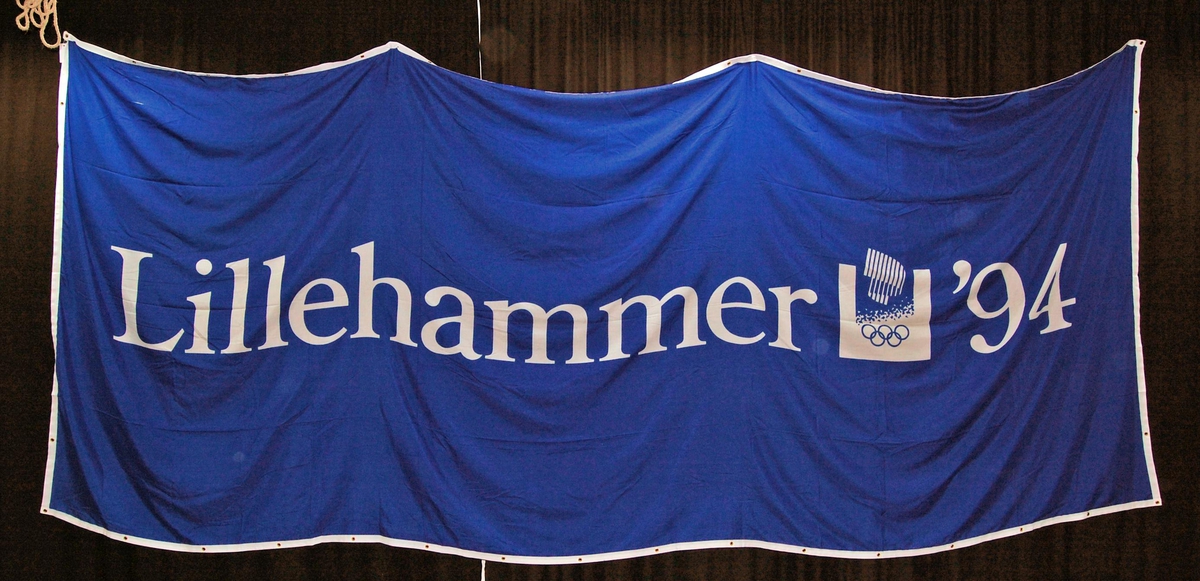Blått banner med hvite kanter. Banneret har logo for de olympiske vinterleker på Lillehammer i 1994.