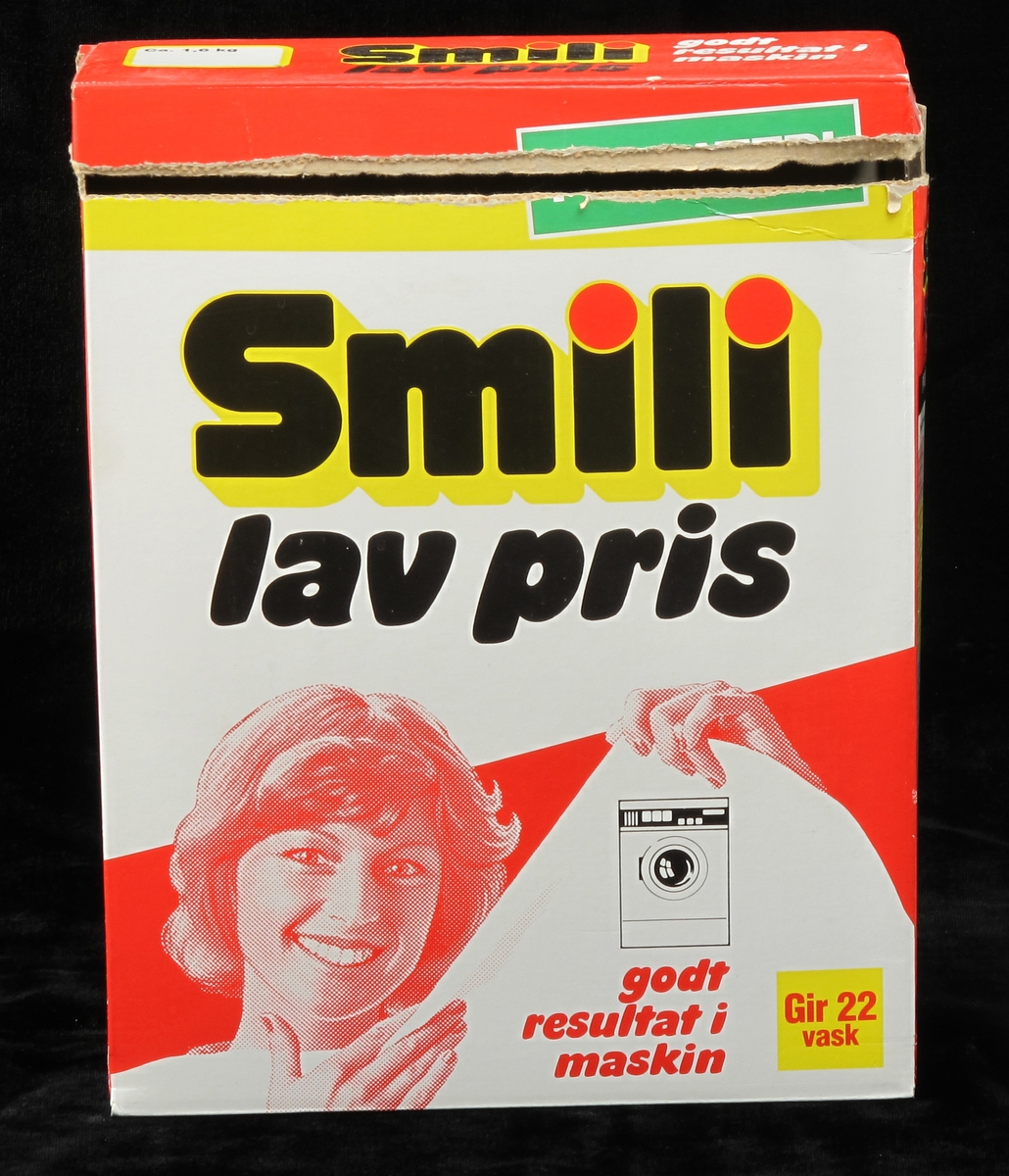 Smilende husmor holder opp hvitt tøy. Vaskemaskin.