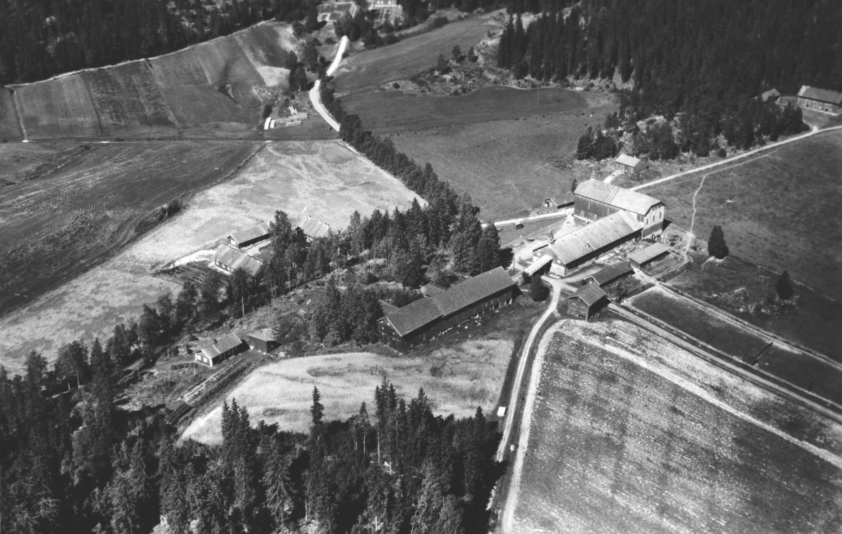Flyfoto av driftsbygningene på Losby bruk. Skolehuset bak.
