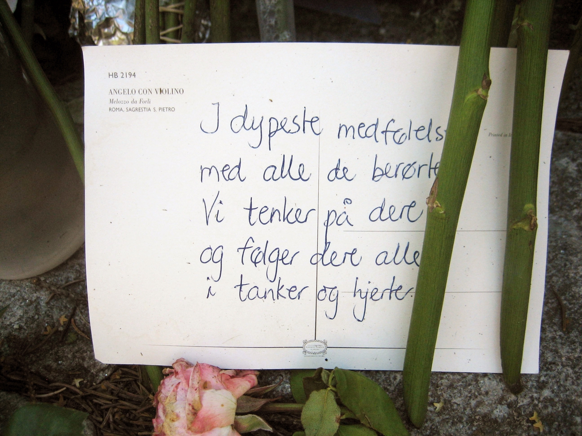 Minner etter terrorhandlingen den 22. juli 2011. Kort  og blomster ved Krigsmonument ved Lillestrøm kirke.
