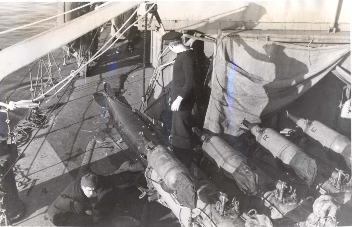 Enkeltbilde. Jageren "Stord" under oppøving, klarsjøing. En torpedo blir tatt ut av en av rørene for å bli sett over mens skipet ligger til land i Scapa Flow.