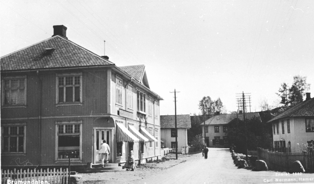 Postkort, Furnesvegen, Helgeby, Brumunddal kooperativ. Samvirkelagsbestyrer Ole Gropen f.1890 inn butikkdøra.