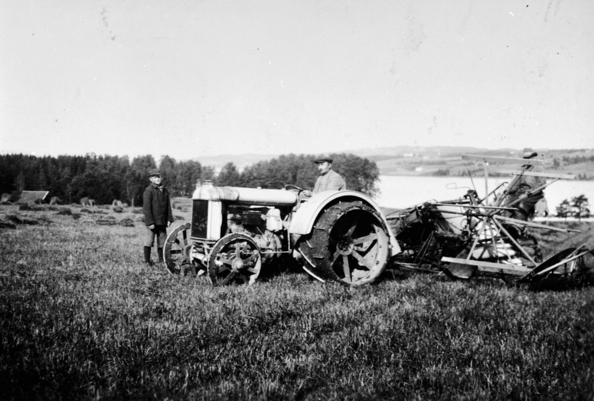 Våronn på Nedre Sund, Helgøya. Den første jerntraktoren på garden med selvbinder. På traktoren er Adolf Solheim f.1877. På selvbinder er Martin Jonsen Gaaserud (1877-1953).