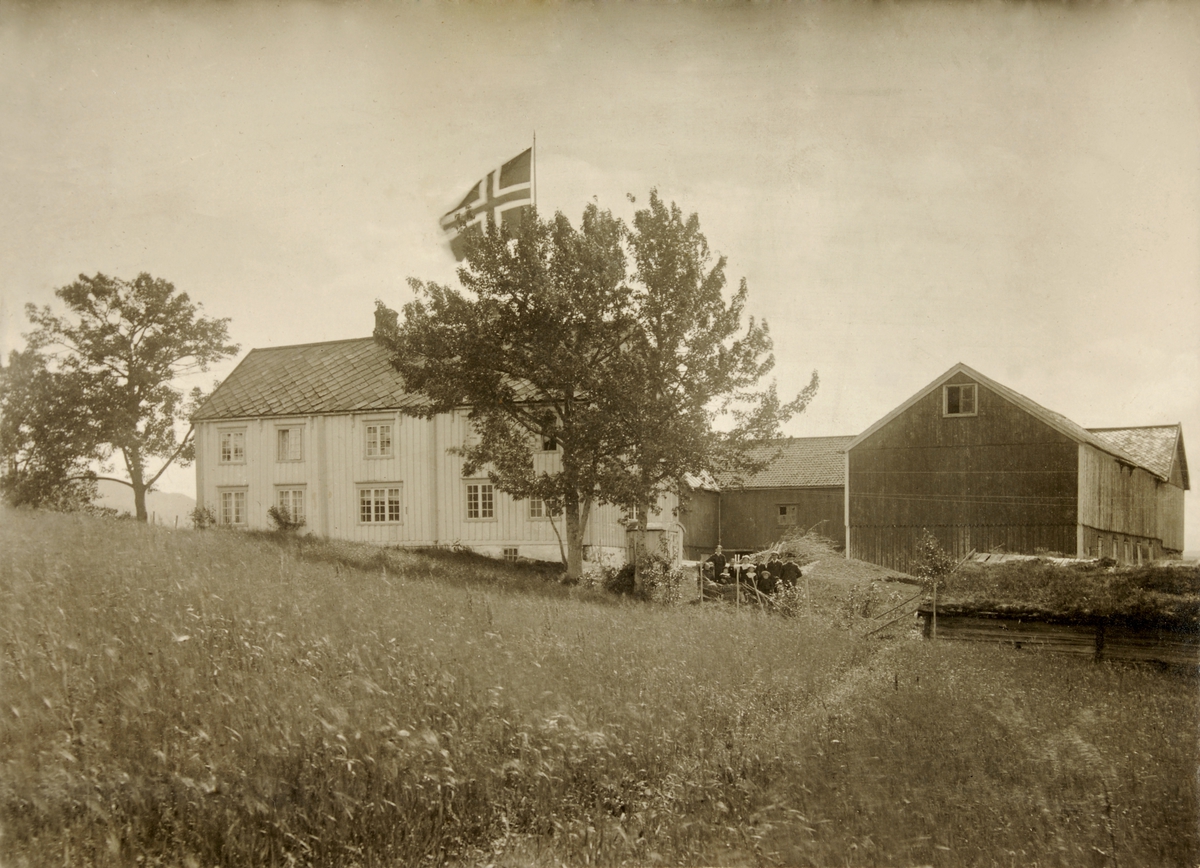 Svart-hvitt fotografi av Klæt gård, vestre. Fotografiet er montert på en grå papplate med organisk dekor i hjørnene av en illudert ramme.