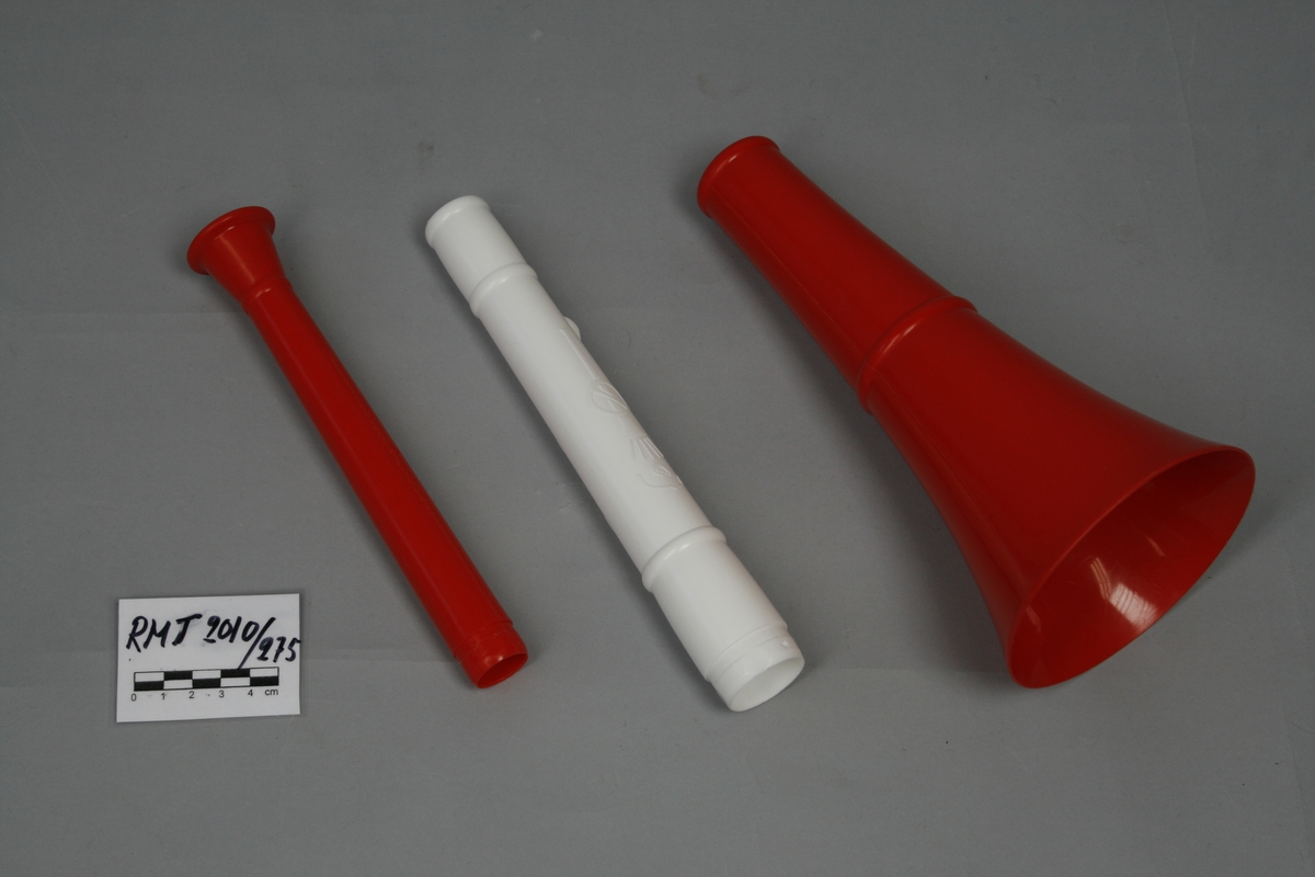 Trompett i tre deler av hvit og rødt plast, tilsvarende farger til Sveits landslag i fotball. Grunntone "B". Demontert kan delene oppbevares inn i hverandre for transport.