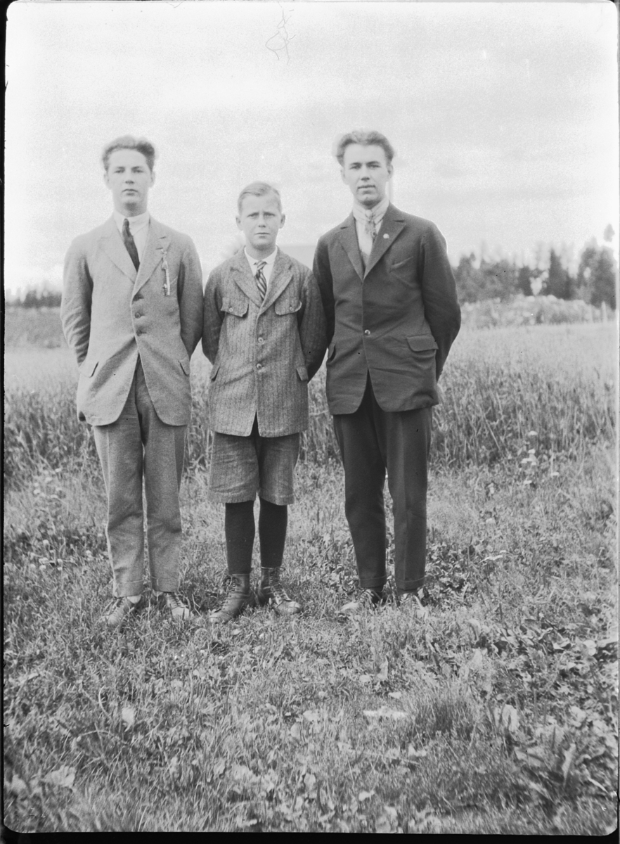 Tre ukjente gutter i dress på et jorde. 