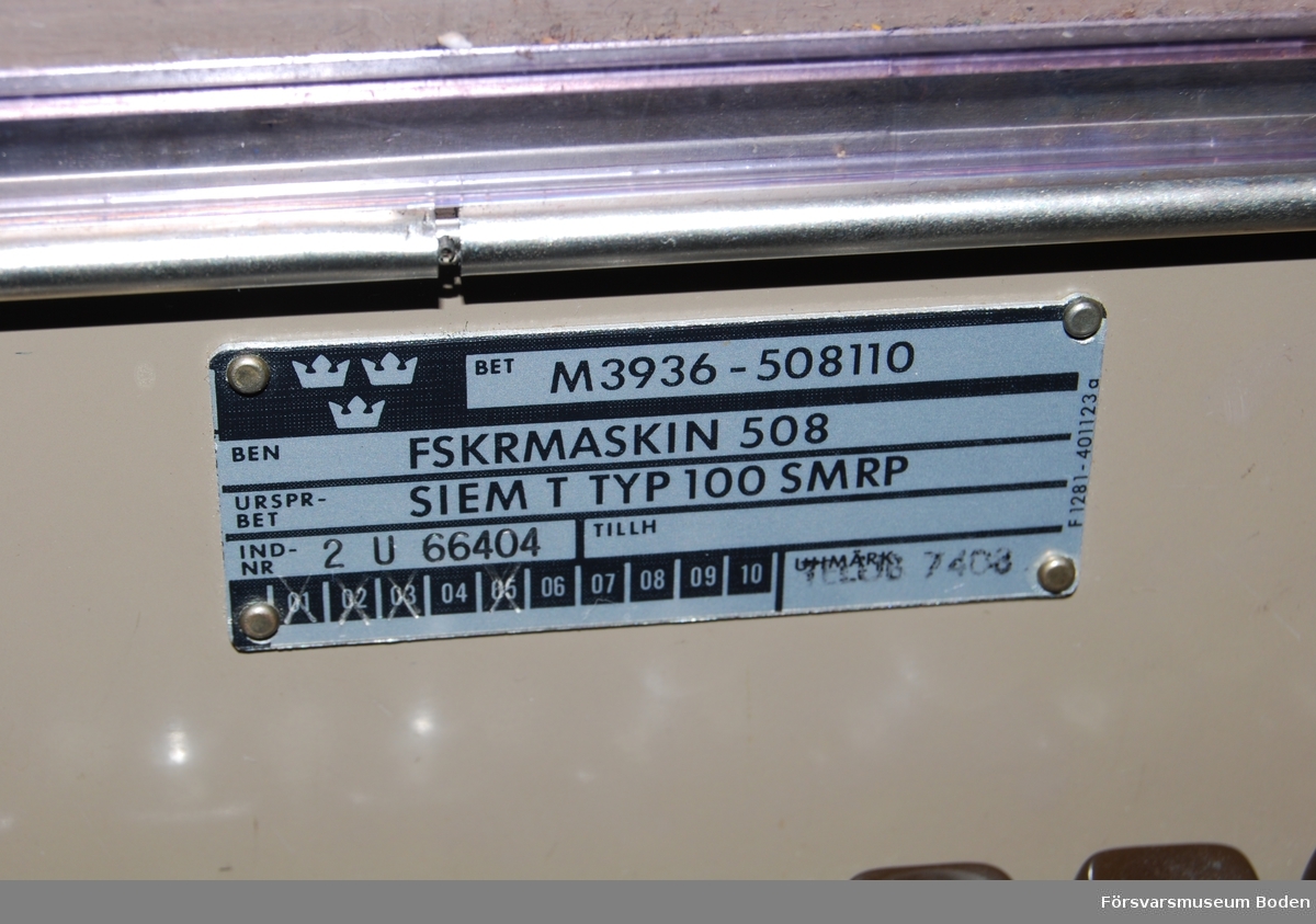 Står på rullbord, transportlådan saknas. Ursprungsbeteckning Siemens typ 100, individnr 2 U 66404. Pappersrulle och remsa är monterade. Enligt etiketter inuti locket var sista översyn 14/1 1982, och föregående 08 1974. Har använts vid AF 1 i Boden.