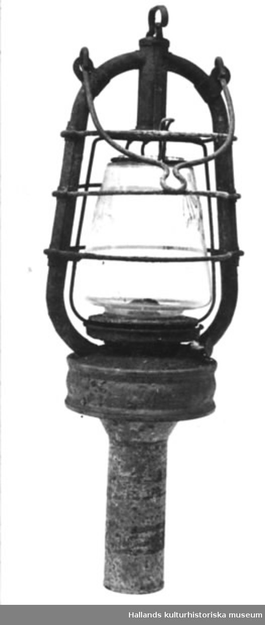 Fotogenlampa (böjlykta) av glas. Hylsan placerad centralt under lyktan. Glas med firmamärke: fladdermus samt O.R.G.M.