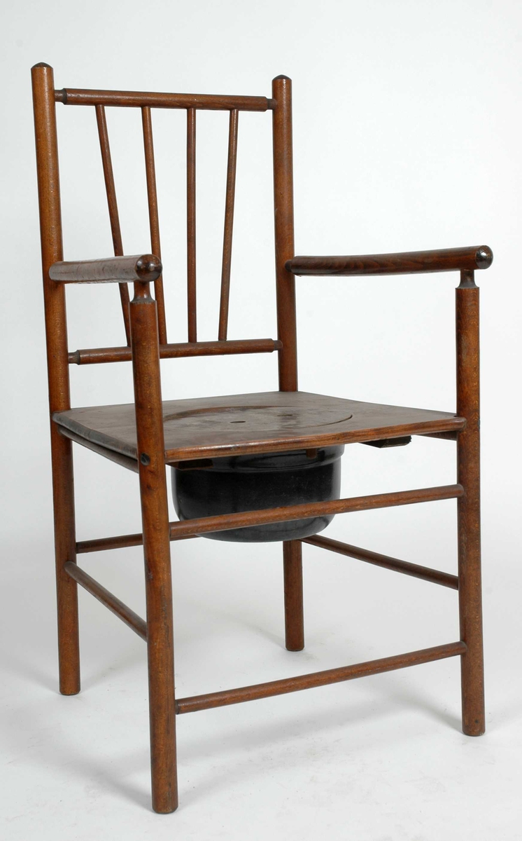 Nattstol fra 1960/70-årene i form av pinnestol i stolpekonstruksjon. Sirkelrundt lokk i setet med to fingerfordypninger. Emaljert potte henger i to påspikrede glideskinner under setet.
