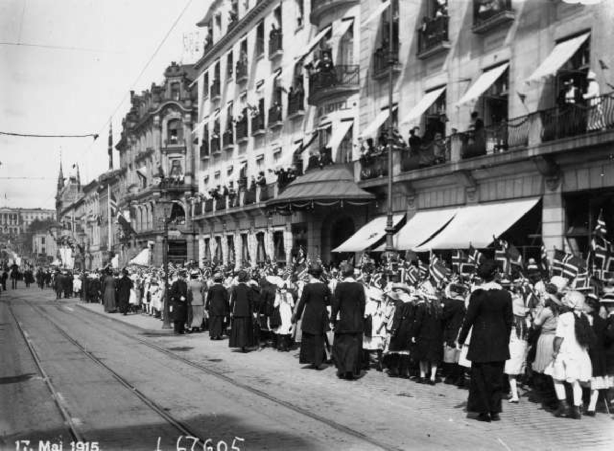 Oslo. 17. mai-tog 1915 ved Grand hotell på vei opp mot Slottet i bakgrunnen.  Publikum på balkongene på Grand hotell.