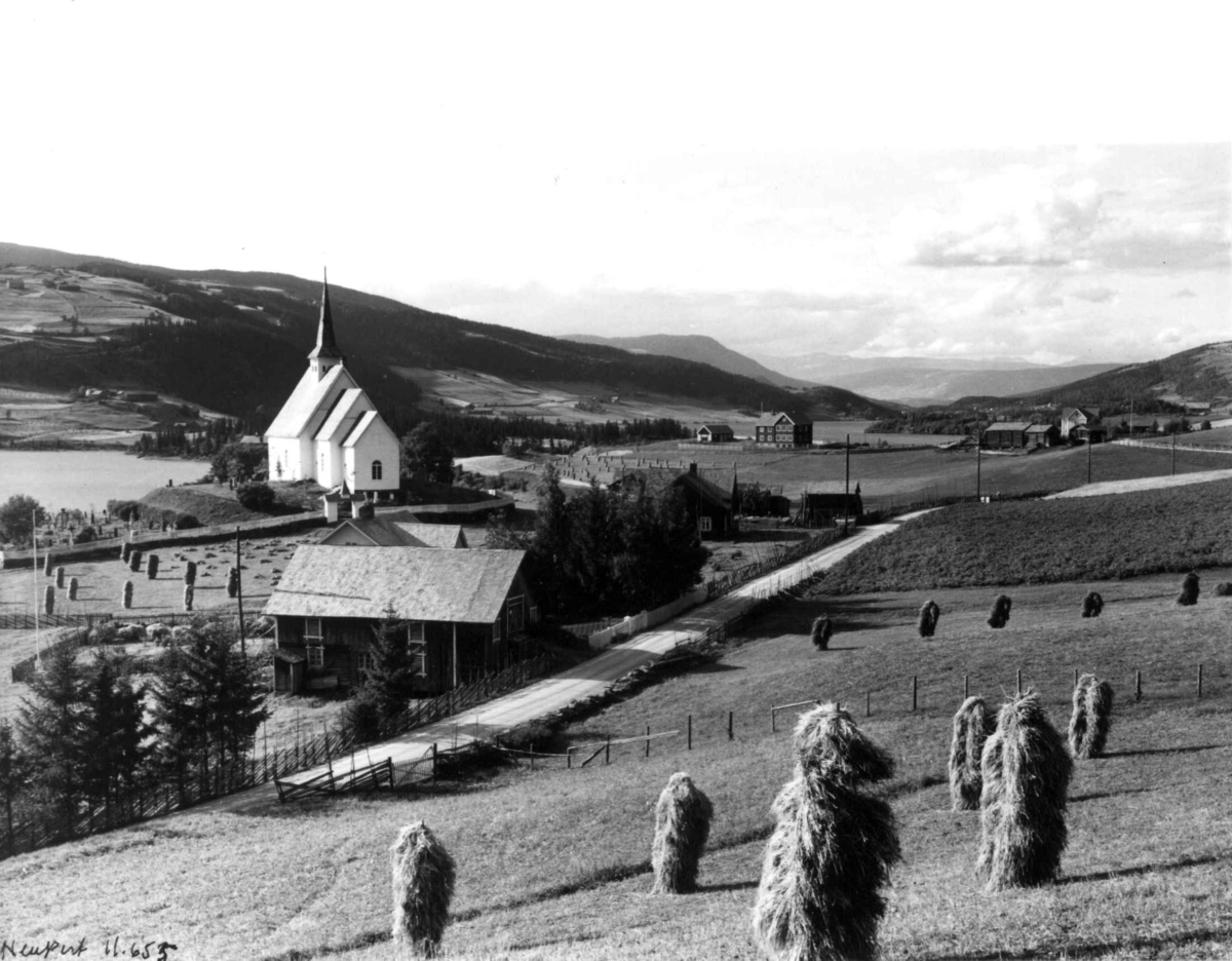 Ulnes kirke, Oppland 1934. Jordbruksbygd med gårdsanlegg. Skurdonn. Vei gjennom bygda. Omgitt av åser. Fjell i bakgrunnen. 