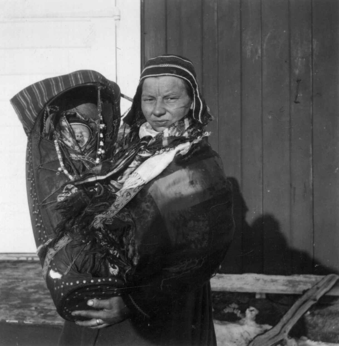 Fastboende kvinne i Kautokeino med sitt barn i komse. Finnmark.