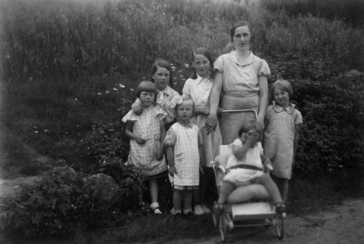 Fru Tamine Vatne sammen med fem barn og et barn i barnevogn. Eiken 1937.